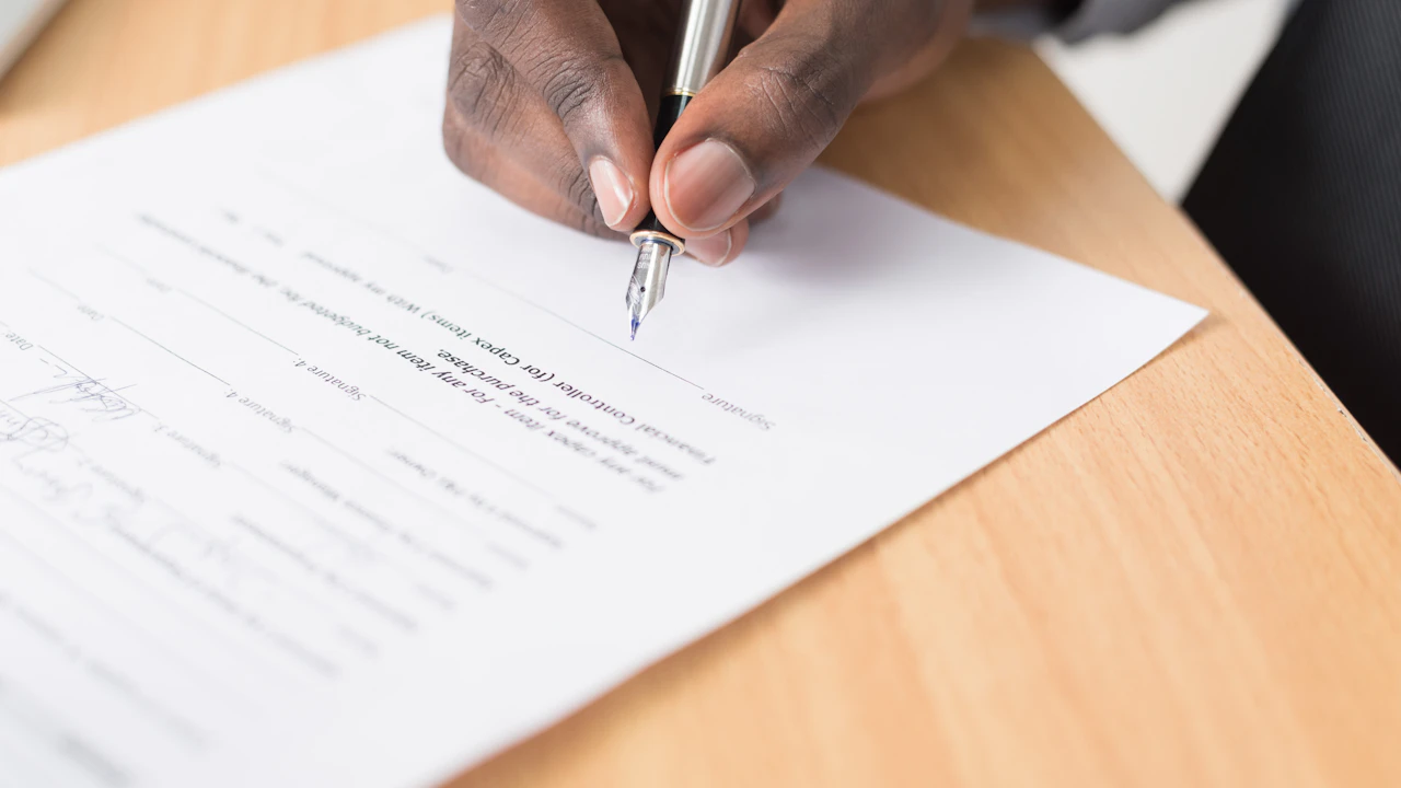 Une personne écrit sur un document posé sur une table.