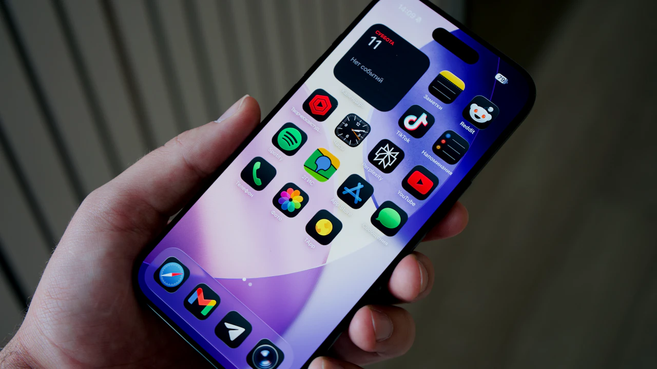 Une main tient un téléphone affichant des icônes d’applications.
