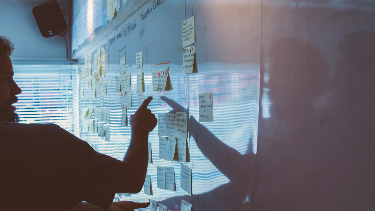 Des personnes examinent des documents affichés sur un mur.