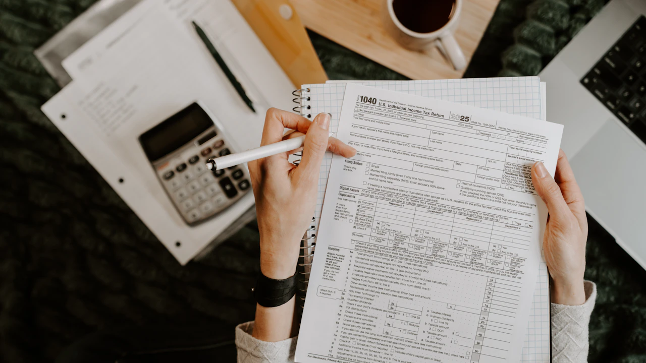 Une personne examine des documents avec une calculatrice et un ordinateur.